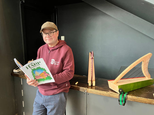 Our harp maker reading his copy of the folk harp journal next to two of his  discovery 16 harps made in Wales